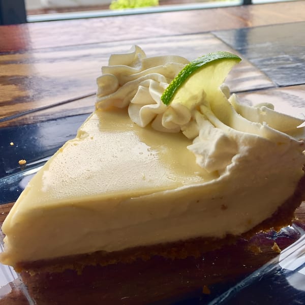 A slice of Key Lime Pie from Slice Of Humboldt Pie, topped with whipped cream and a lime wedge.